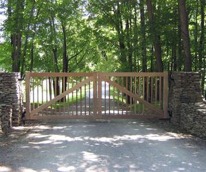 Natural cedar wood gate with vertical posts and wooden cross beam by Tri State Gate, New York
