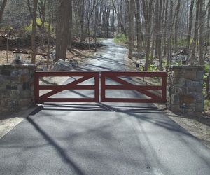 Minimalist farm-style wooden driveway gate with deep mahogany stain by Tri State Gate, New York