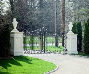 Custom, wrought-iron gate design with concrete pillars and decorative statues. Installed by Tri State Gate, Bedford Hills, New York.