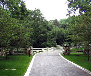 Clean, ranch-style automated gate with stone pillars by Tri State Gate, New York