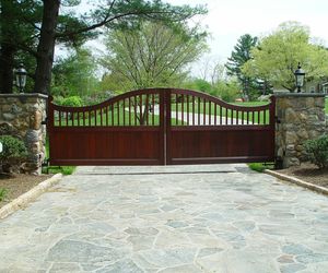 Custom-designed mahogany wood entry gate with natural stone pillars by Tri State Gate, New York