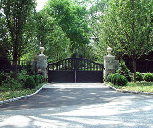 Ranch driveway gate with stone-wrapped pillars and statues, by Tri State Gate, New York