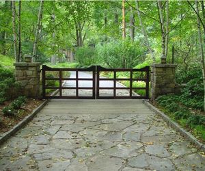 Vintage-style wooden swing gates with stone-wrapped posts by Tri State Gate, New York